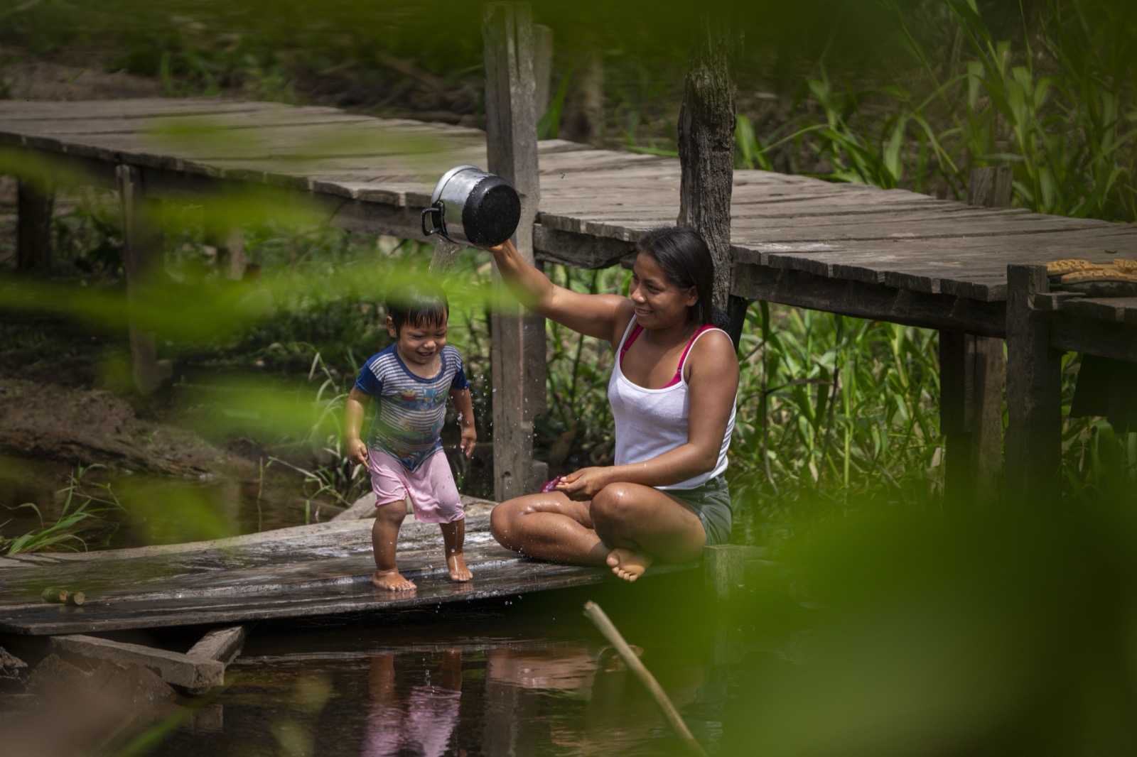 Mother bathing child on wooden dock