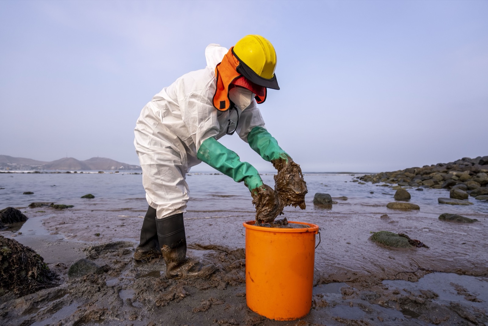 Oil spill cleanup worker on beach